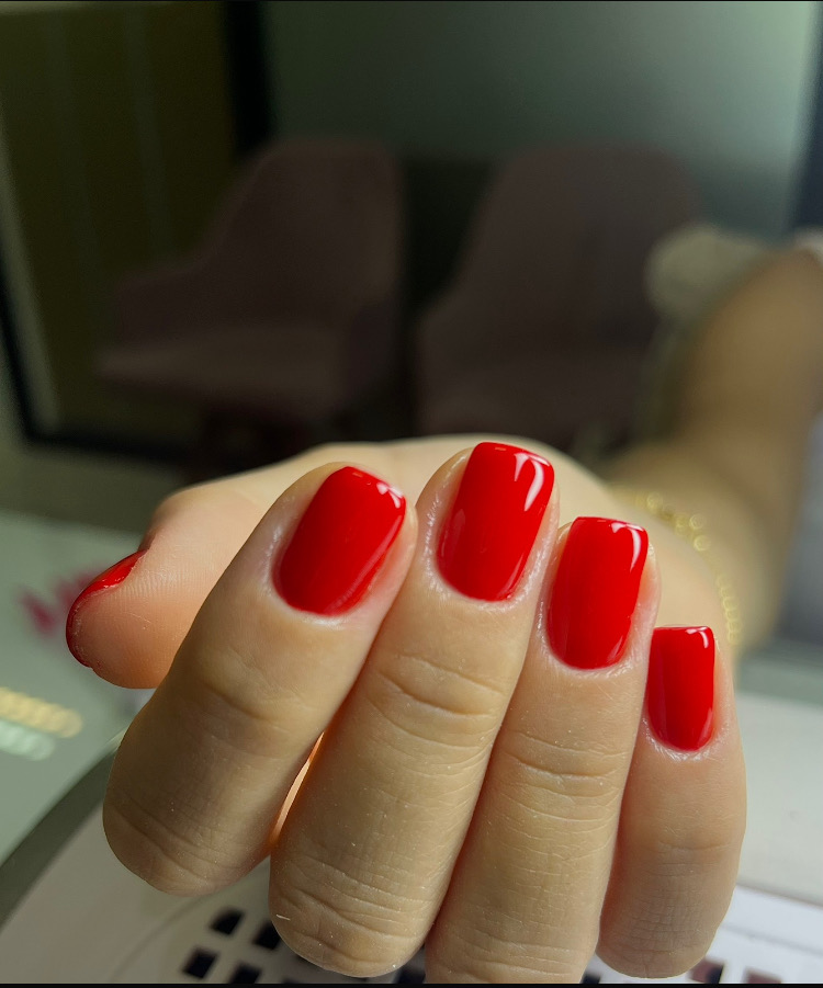 Unhas quadradas com esmaltação vermelha e acabamento brilhante